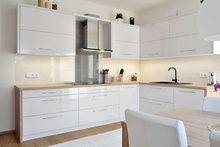 Kuchyňe je navržena v provedení bílá lesklá v kombinaci s pracovní deskou v dekoru přírodního dubu.