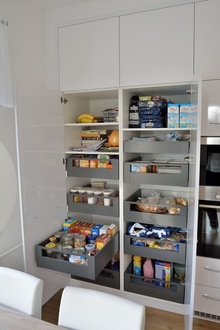 Pohled na otevřenou skříň s vysouvacími šuplíky na potraviny.